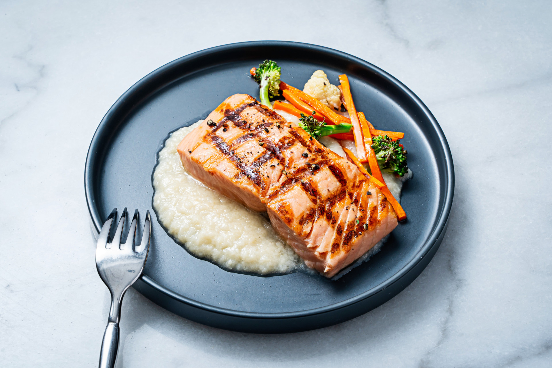 Grill seared salmon over mashed cauliflower next to mixed vegetables on plate