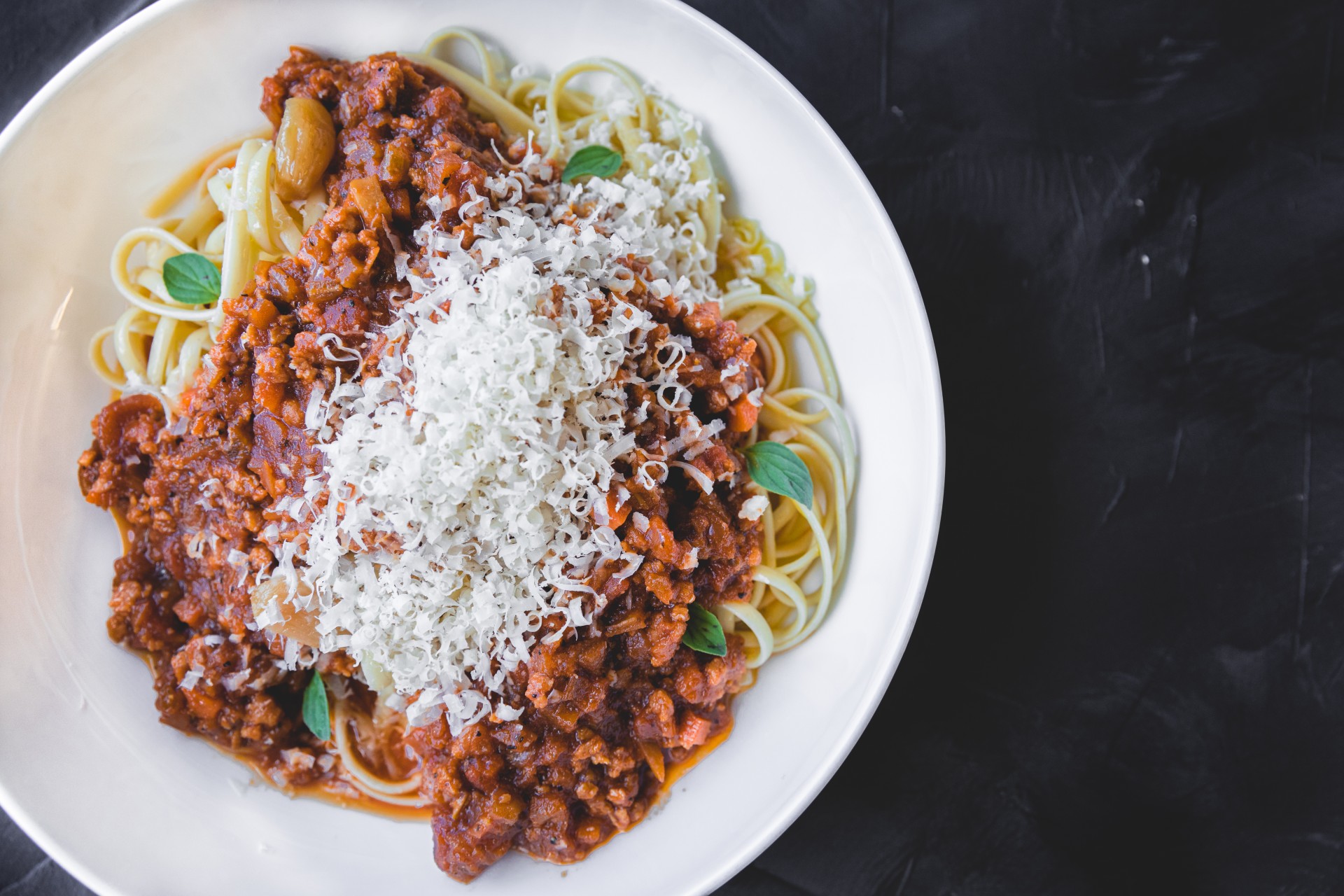 Vegan Bolognese over fettucine noodles on a white plate